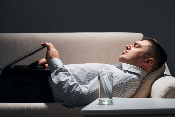 бізнесмен лежить на дивані з ноутбуком і відпочинком
 - Фото, зображення