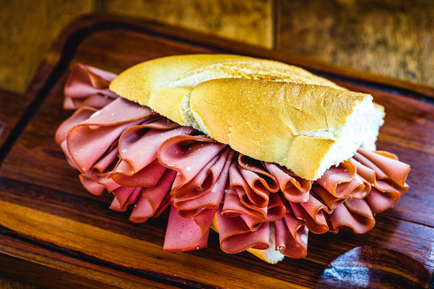 bread with mortadella and melted cheese. Rustic wooden background, Sao Paulo meal, famous bread and mortadella from So Paulo market. - Photo, Image