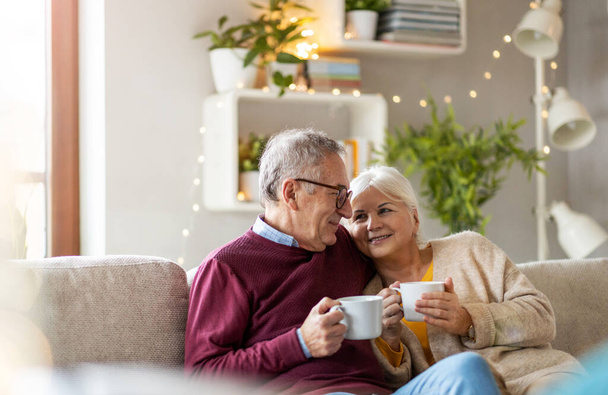 Muotokuva onnellisesta vanhasta pariskunnasta rentoutumassa yhdessä sohvalla kotona
 - Valokuva, kuva