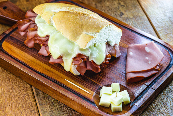 Chléb s mortadellou a roztaveným sýrem. Rustikální dřevěné zázemí, Sao Paulo jídlo, slavný chléb a mortadella z So Paulo trhu. - Fotografie, Obrázek