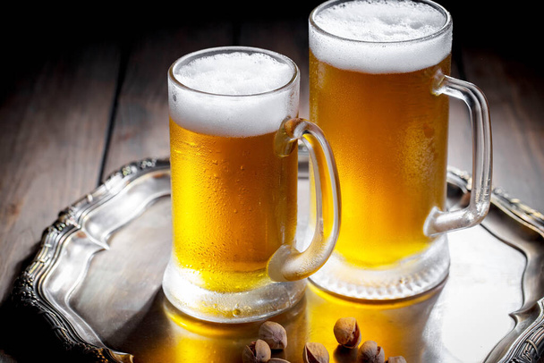 Ελαφριά μπύρα σε ποτήρι πάνω σε τραπέζι σε σύνθεση με αξεσουάρ σε παλιό φόντο - Φωτογραφία, εικόνα