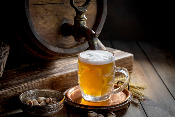 Ελαφριά μπύρα σε ποτήρι πάνω σε τραπέζι σε σύνθεση με αξεσουάρ σε παλιό φόντο - Φωτογραφία, εικόνα
