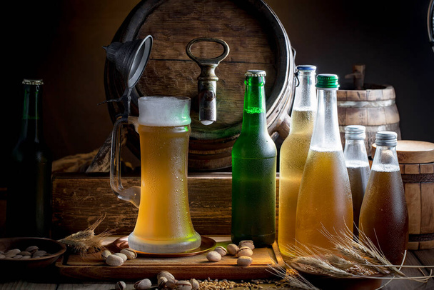 Licht bier in een glas op een tafel in compositie met accessoires op een oude achtergrond - Foto, afbeelding