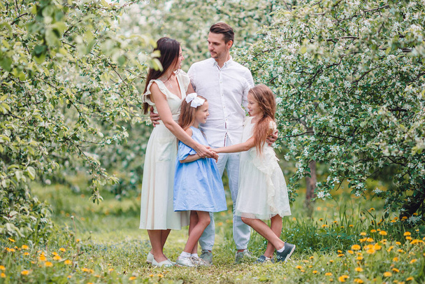 Urocza rodzina w kwitnącym wiśniowym ogrodzie w piękny wiosenny dzień - Zdjęcie, obraz