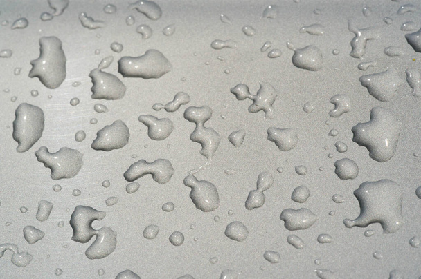 καλοκαιρινή βροχή, σταγόνες νερό στην μπογιά του αυτοκινήτου. ένα μικρό στρογγυλό ή αχλάδι σε σχήμα τμήμα υγρού που κρέμεται ή πέφτει ή προσκολλάται σε μια επιφάνεια. - Φωτογραφία, εικόνα