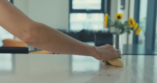 A woman's hand is cleaning up a spillage from the kitchen counter in a modern city apartment - Кадри, відео