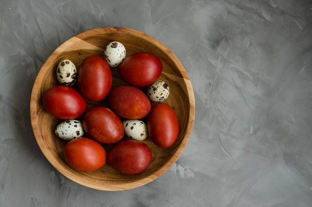 Concepto de Pascua. Huevos de Pascua naturales en un tazón de madera cocido en cáscaras de cebolla sobre un fondo de piedra oscura. Orientación horizontal. Enfoque selectivo. Vista superior. Copiar espacio
 - Foto, imagen