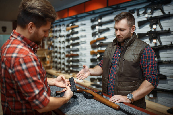 Uomo e proprietario che scelgono fucile e pistola nel negozio di armi. Euqipment per i cacciatori in negozio di armi, caccia e tiro sportivo hobby, sicurezza e autodifesa
 - Foto, immagini