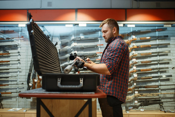 L'uomo prende il fucile da cecchino dal caso nel negozio di armi. Euqipment per i cacciatori in stand in negozio di armi, caccia e sport hobby tiro
  - Foto, immagini
