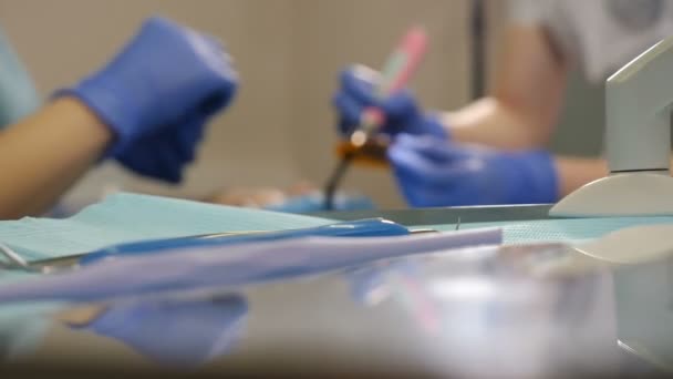 Dental blurred treatment shot through tools on table. Dentist and nurse at work, close-up. Patient Undergoes Medical surgical operation and Oral Cavity Treatment at modern dentistry. 4 k video - Felvétel, videó