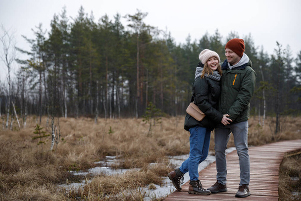 couple on a walk in the woods. Girl and boyfriend walk in nature in jackets and hats. - Photo, Image