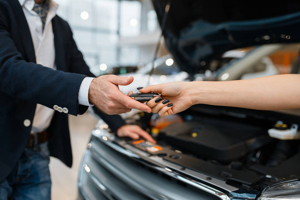 Man and salesgirl choosing auto in car dealership. Customer and seller in vehicle showroom, male person buying transport, automobile dealer business - Foto, Bild
