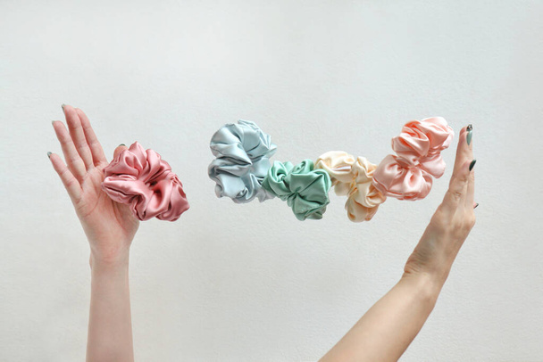 Lot of floating Colorful silk Scrunchies on womas hands isolated white. Hairdressing tools and accessories. Hair Scrunchies, Elastic HairBands, flying or falling Scrunchie Hairband for girls or ladies - Photo, Image