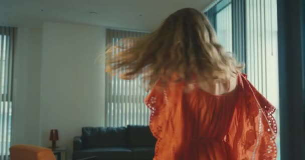 A young mother wearing a red dress is spinning around in her city apartment with her little toddler son - Séquence, vidéo