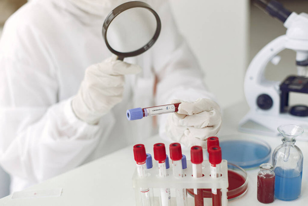 Scientist in coverall clothing is examining coronavirus sample in a laboratory - Fotó, kép