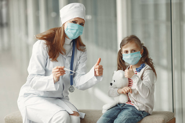 Doctor and a child in protective masks are in hospital - Фото, изображение