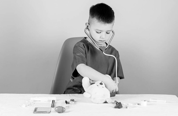 Medicine concept. Medical procedures for teddy bear. Medical education. Boy cute child future doctor career. Health care. Kid little doctor busy sit table with medical tools. Medical examination - Photo, image