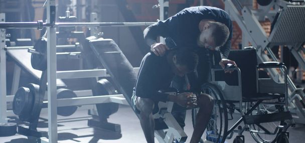 Wheelchair man lifting weight in gym - Foto, imagen