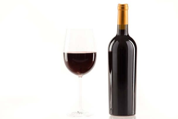 Ένα ποτήρι κόκκινο κρασί με ένα μπουκάλι δίπλα του. - Φωτογραφία, εικόνα
