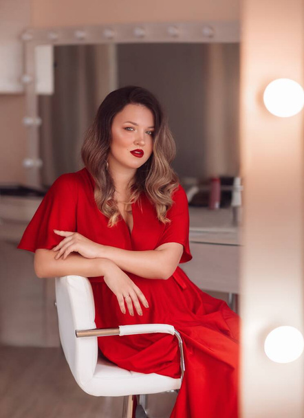 portrait of beautiful woman in red dress near the mirror - Foto, Bild