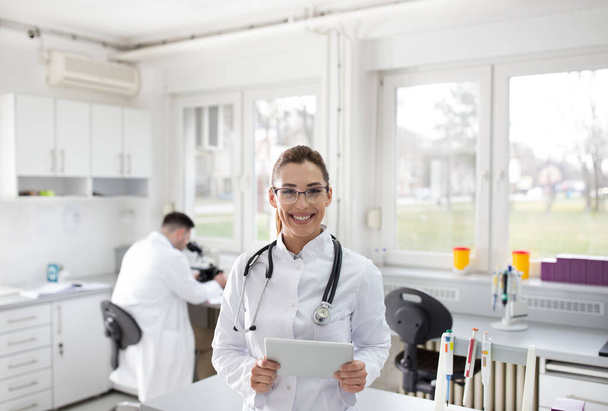 Portrait of confident female doctor with tablet standing in laboratory - Φωτογραφία, εικόνα