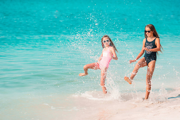 Little happy funny girls have a lot of fun at tropical beach playing together. - Photo, Image