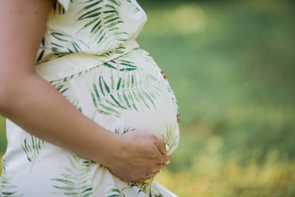 Κοντινό πλάνο. Πορτρέτο μιας όμορφης νεαρής εγκύου με οικολογικό φόρεμα. Μητρότητα. Μια οικογένεια. Καλοκαίρι. - Φωτογραφία, εικόνα