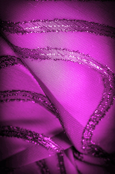 орнамент декора, прозрачная ткань фиолетово-красного цвета с ярко врожденными полосами, материал, позволяющий свету проходить через него так, что объекты позади четко видны
. - Фото, изображение