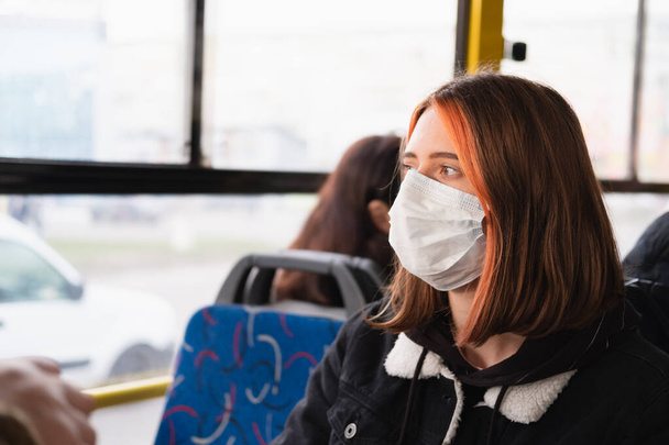 Woman commutes in a protective face mask. Coronavirus, COVID-19 spread prevention concept, responsible social behaviour of a citizen - Photo, image