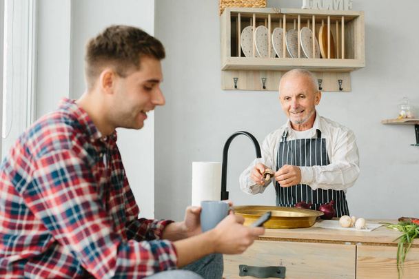 Young man and his father cooking in kitchen - Photo, Image