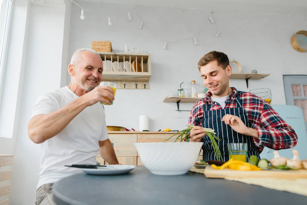 Молодой человек и его отец готовят на кухне
 - Фото, изображение