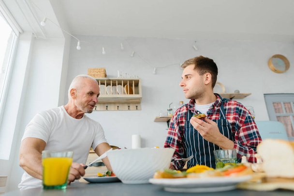 Young man and his father cooking in kitchen - 写真・画像