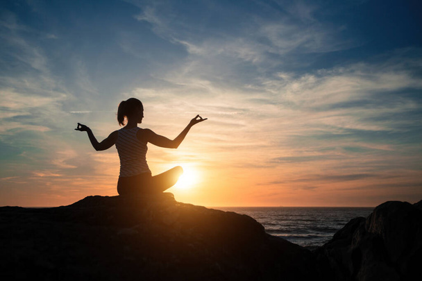 Silhouette Frau praktiziert Yoga am Strand bei herrlichem Sonnenuntergang. - Foto, Bild