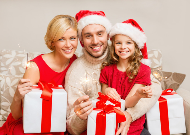 Smiling family holding gift boxes and sparkles - Photo, image