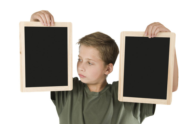 Torso view of a 13-year-old male teenager against a white background in both hands holding a black plaque about 30 cm tall next to him at the height of his head and looking at the left panel - Photo, image