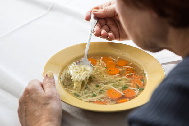 Τρώγοντας στο σπίτι μαγειρεμένη σούπα με καρότα και νουντέλ - Φωτογραφία, εικόνα