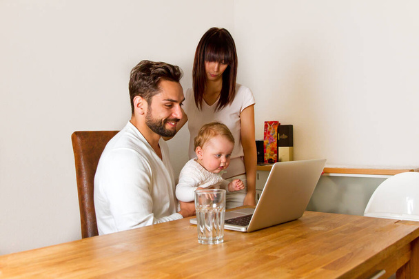 счастливая семья с ноутбуком дома - Фото, изображение