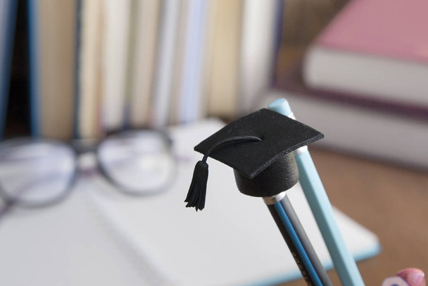 A cap of education on a pencil against the background of books a - Photo, image