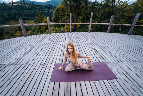 Una mujer practica yoga por la mañana en una terraza al aire libre
. - Foto, Imagen
