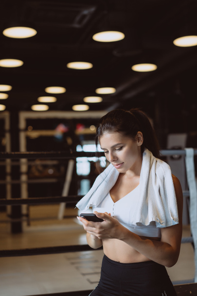 Girl texting while taking a break in a gym. Reads a message - 写真・画像