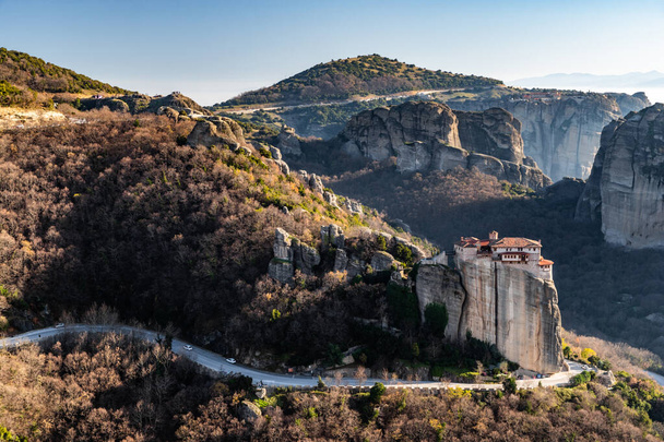 Aerial view of monastery Rousanou and breathtaking picturesque valley and landmark canyon of Meteora at sunset, Kalambaka, Greece, shadows, twisted road, bridge - Фото, изображение