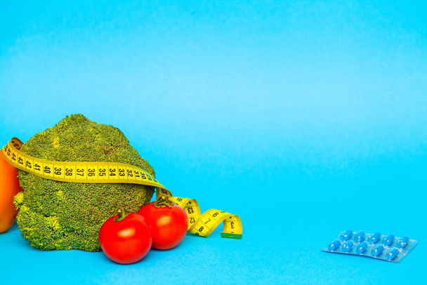 Pillen voor gewichtsverlies en meetlint op een blauwe achtergrond - Foto, afbeelding