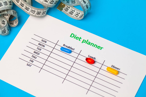 Plan de dieta y píldoras de pérdida de peso en el fondo azul
 - Foto, imagen
