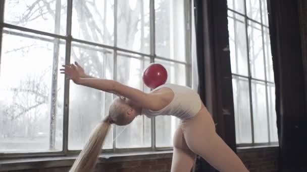 Girl in a loft studio shows exercises with rhythmic gymnastics - Imágenes, Vídeo