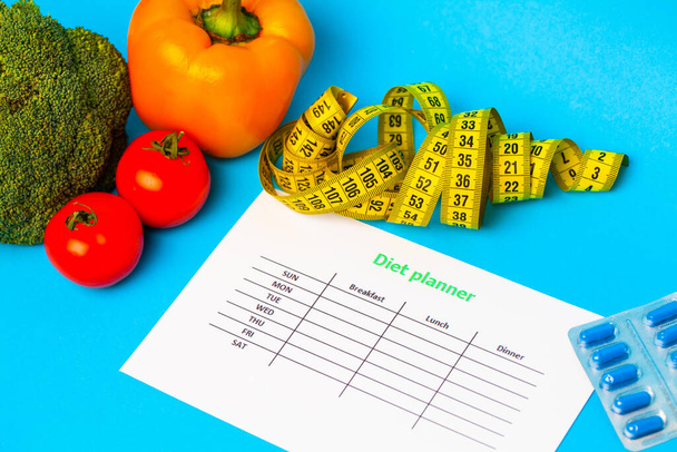 Plan de dieta, para las píldoras de pérdida de peso y verduras frescas sobre un fondo azul
 - Foto, imagen