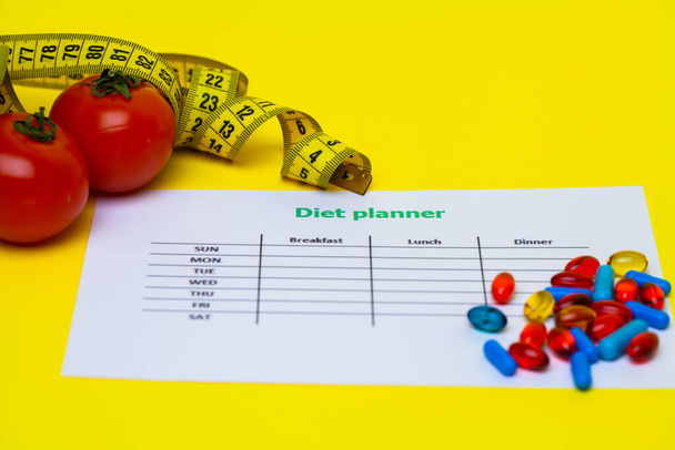 Plan de dieta y píldoras de pérdida de peso en un fondo amarillo
 - Foto, imagen