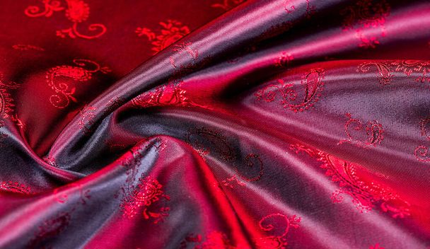 Textur, Stoff, rote Seide mit Paisley-Muster. Diese wunderschön bedruckte Charmeuse aus Seide hat ein gewagtes Paisley-Muster. In der patriotischen Erscheinung gibt es Farben rot, der Stoff hat eine rutschige Hand - Foto, Bild