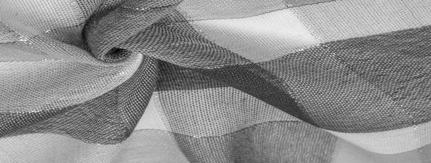 Textur, Hintergrund, Seidentuch feminin schwarz-weiß mit einem Metallstreifen. Der Schal ist mit einem zarten Patchwork-Muster in Pastellfarben mit abstrakten schottischen Motiven verziert. kariertes Gewebe - Foto, Bild