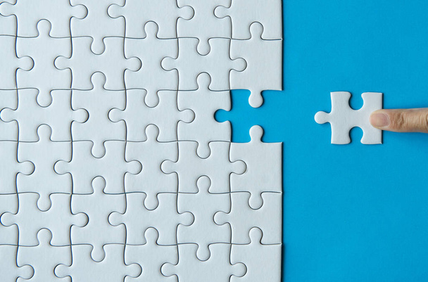 Woman hands putting Jigsaw puzzles,Jigsaw white color,Puzzles pieces grid,Success mosaic solution template,Concept of teamwork and business - Fotó, kép