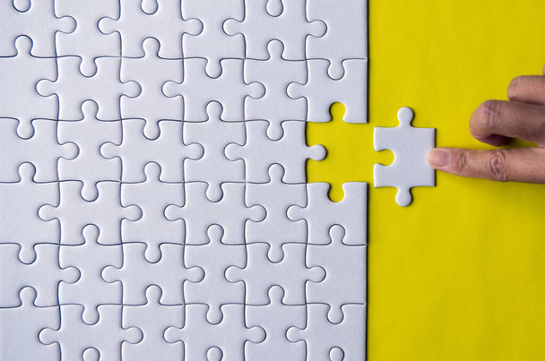 Woman hands putting Jigsaw puzzles,Jigsaw white color,Puzzles pieces grid,Success mosaic solution template,Concept of teamwork and business - Fotó, kép
